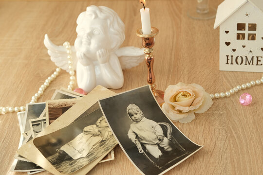stack of vintage photos on table, romantic still life in love style, cupid with wings, candles burning, concept of family tree, genealogy, childhood memories