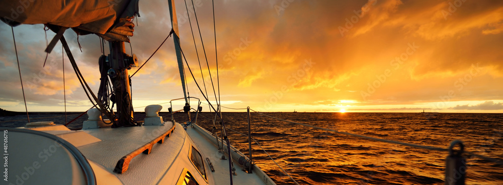 Wall mural white yacht sailing in an open sea at sunset. a view from the deck to the bow, mast, sails. epic clo - Wall murals