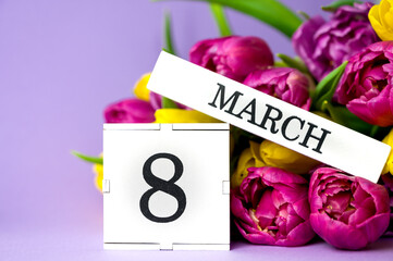 Cube calendar with date MARCH 8 and beautiful bunch of tulips s for International Women's Day celebration on light background