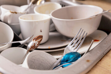 Pile of unwashed, dirty dishes in the sink. Mess in the kitchen. Dirty kitchenware, plates and mugs. Chaos at home. Laziness. Cluttered apartment. Messy cutlery and dishware.