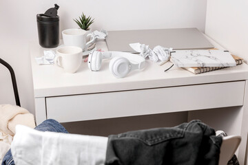 Messy table with laptop, dirty cups, and stationary items. Cluttered workplace, desk. Concept of...