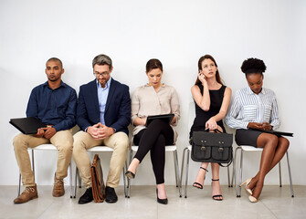 Eager to make a good impression. Shot of a group of businesspeople seated in line while waiting to...
