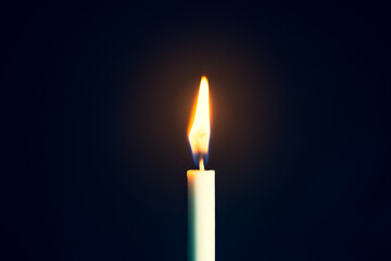 One light candle burning brightly in the black background 