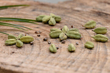 closeup the bunch green ripe cardamom with green leaves over out of focus wooden background.