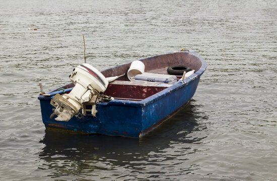 Empty and old fishing boat with engine moored on the blue sea