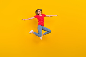 Full length photo of young excited lovely girl jump arms balance airplane isolated over yellow...