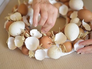 woman arranges an easter wreath of eggshells