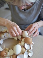 woman arranges an easter wreath of eggshells