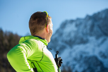 Caucasian man, with ski sunglasses, taking pleasure in observing beautiful winter nature and...