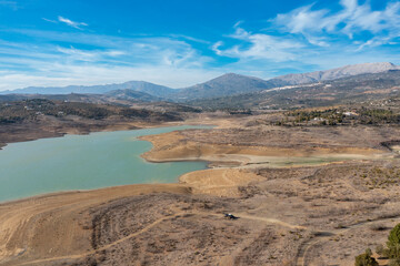 An aerial view of Lake Vinuela in the backcountry mountains of Malaga Province with a tiny camper van below