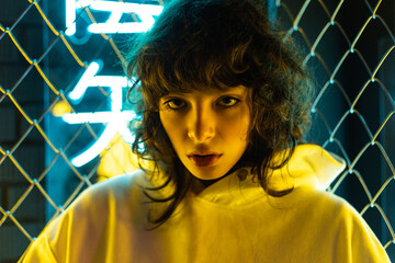 Portrait of a beautiful young woman with curly hair in neon lighting. Hieroglyphs: Nirvana, time...