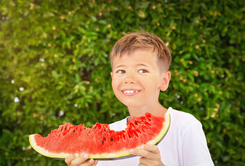 Happy nine years old child (boy) eating a red juicy watermelon. Caucasian kid smiling and having fun. Concept of healthy food, happy childhood, summer vacation. Healthy lifestyle. Copy space.