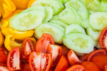 Chopped cucumbers, tomatoes and sweet peppers close-up.