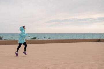 Caucasian woman in mint sweatshirt doing jogging outdoors. 