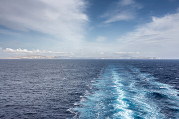 Wake in the Aegean Sea from Cruise Ship. In the background the island of Santorini, Greece