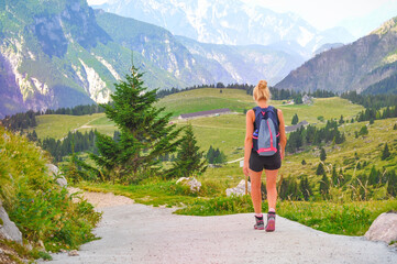 hiker girl walk climbing up down background of the Italian Alps