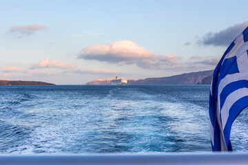 cruise ship anchoring in the Aegean Sea, Santorini Island, Seen from speedboat with Greek flag. Greece.