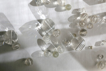 Various transparent beads on white background, illuminated by sunlight and reflectiing light. Flat...
