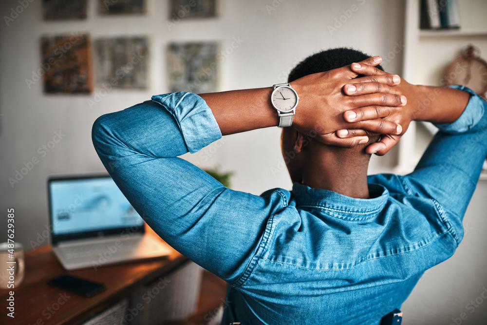 Poster Enjoying the entrepreneurial life. Rearview shot of a handsome young businessman sitting in his home office with his hands behind his head in accomplishment.