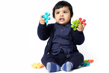 Happy Indian Toddler Playing With Colorful Toys Isolated On White Background. Fun, Activity, Educational, Kindergarten, Birthday, Learning, Home Activity, School, Nursery, Daycare Engagement Concept