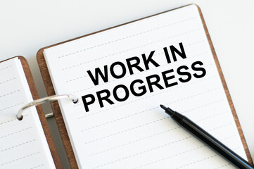 Work in Progress text written on a notebook with pencils
