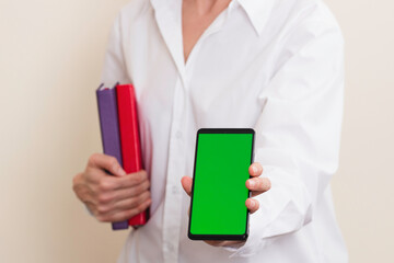 Woman hands holding books and smartphone with blank green screen background