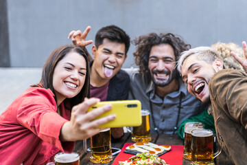 Young people having fun taking a selfie pic at bar restaurant - Happy multiracial friends drinking beer at outdoors brewery pub