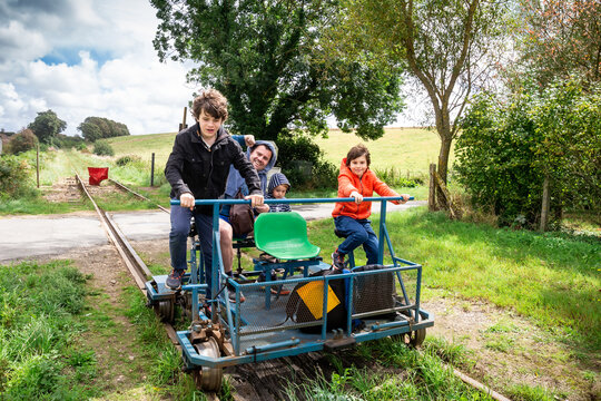 Family enjoying the rail bike attraction in France, Normandy. Father and sons on rail trolley.