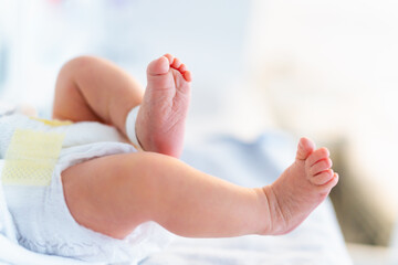 Newborn legs close up. Child birth, first day in hospital, newborn baby wearing diaper  in postpartum department.