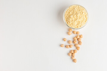 Chickpea flour in a glass bowl and chickpeas beans on a white background top view with copy space
