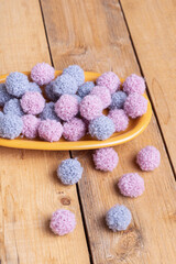 Small fluffy pompoms for decorating on wooden background. Pompoms for creativity