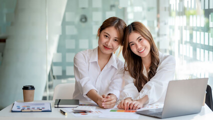 Two pretty Young Asian businesswoman or intern who sitting smile happily in the office. Looking at...