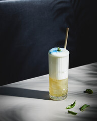 creamy long drink with basil and blue dust on a bar table 