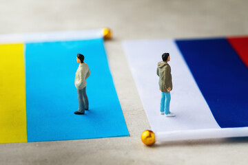 Toy people made of plastic and two flags on an abstract background, a concept on the theme of...
