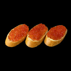 Red caviar on a piece of bread isolated on a black background