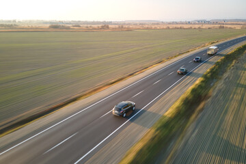 Aerial view of intercity road with fast driving cars at sunset. Top view from drone of highway traffic in evening