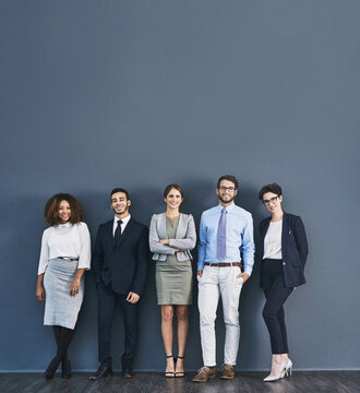 Corporate confidence at its best. Studio shot of a group of businesspeople standing in line against a gray background.