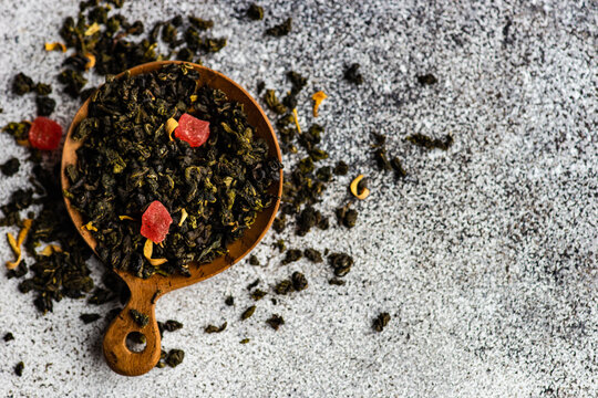 Overhead view of a bowl of green sencha tea leaves with dried mango