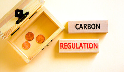 Carbon regulation symbol. Concept words Carbon regulation on wooden blocks on a beautiful white table white background. Wooden chest with coins. Business and carbon regulation concept, copy space.