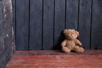 the teddy bear lies in the bedroom in the corner on the wooden floor