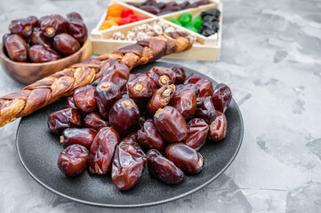 Dried large dates and a spit of dried melon lie on a black plate. Close-up, selective focus. copy space