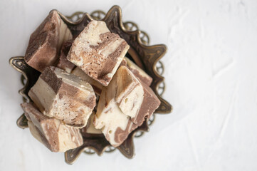 plate with halva from sunflower seeds on a bronze tray, selective focus. Still life with halva in Arabic style. copy space . Top view