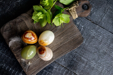 colored onyx spheres on a textured wooden board. Easter eggs made of natural onyx gemstone. Fashionable organization of the spring holiday. top view. copy space