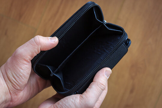 Man Is Holding Open Empty Black Leather Wallet On Wooden Background.