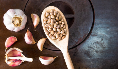 Wooden spoon with carioca beans over wood stove next to garlic cloves.