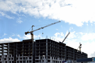 unfinished building and a crane above it. Photo on the topic of housing construction, the risks of investing in real estate.