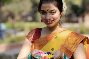 Young and beautiful and smiling girl or woman to celebrate holi festival of coloors in yellow saree...