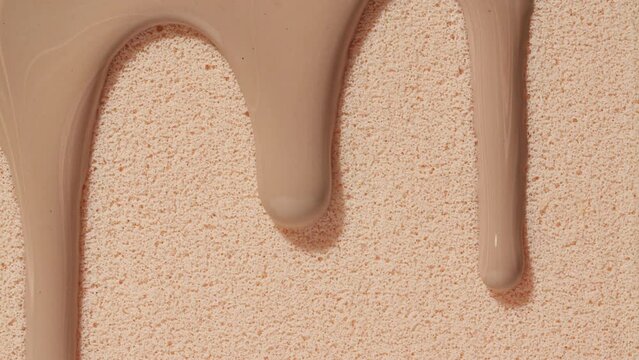 Foundation for face, smear, concealer, cosmetic liquid foundation, or cream beige color smudge flowing down on sponge. Beauty skincare sample. Macro Shot. Close up. High quality 4k footage