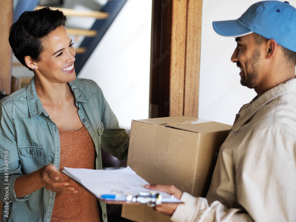 Wall mural Keeping his clients smiling. Shot of a smiling young woman standing at her front door receiving a package from a courier.