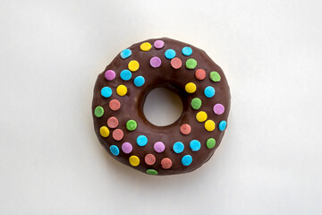chocolate frosted doughnut with colorful confetti on pale background